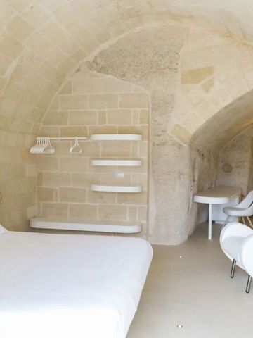 Höhlenzimmer mit weißem Bett und eleganter Einrichtung