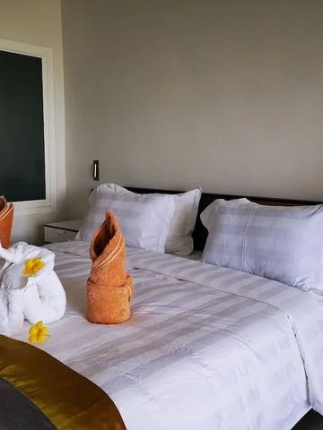 Hotelbett mit eleganter Wäsche und dekorativen Handtuchfaltungen