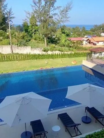 Infinity Pool mit Liegestühlen und Blick ins Grüne und auf das Meer
