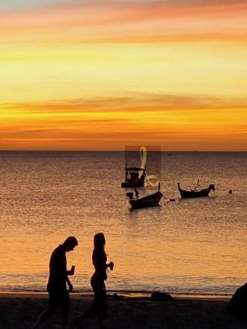 Romantischer Sonnenuntergang am Strand mit traditionellen Booten