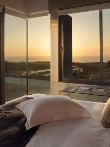Schlafzimmer mit Panoramafenstern und Meerblick bei Sonnenuntergang