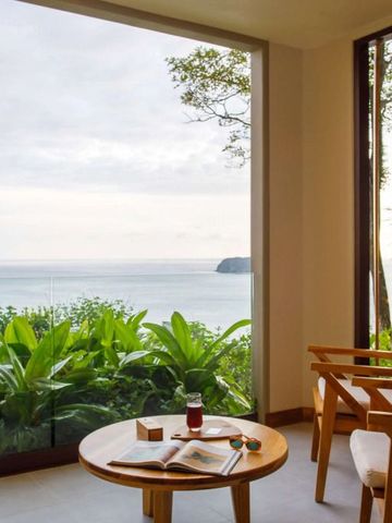 Helle Sitzecke mit Blick auf das Meer durch große Fenster im Hotelzimmer.