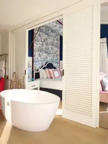 Luxuriöses Badezimmer mit freistehender Badewanne und offenem Schlafzimmerzugang