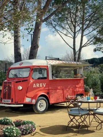 Roter Vintage-Foodtruck im Garten mit Tisch und Stühlen