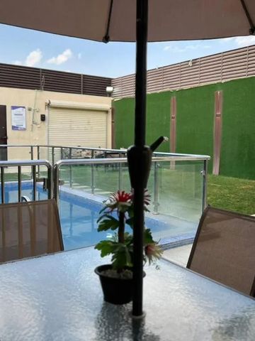 Kleiner Pool mit Tisch und Stühlen unter einem Sonnenschirm im Außenbereich