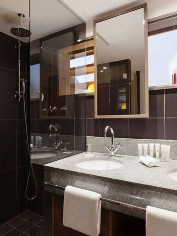 Modernes Bad mit großer Dusche, Doppelwaschbecken und Spiegeln.