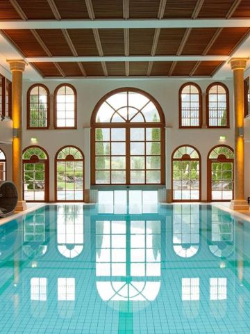 Beheiztes Hallenbad mit großen Bogenfenstern und Säulen