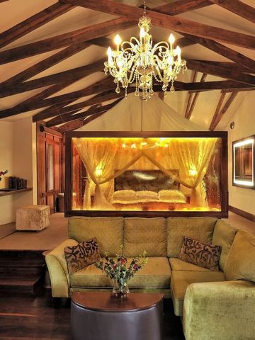 Luxuriöses Zimmer im Arusha Coffee Lodge mit gemütlicher Sofaecke und Kronleuchter