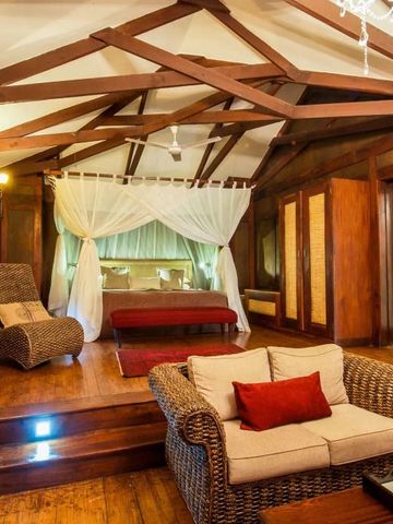 Warmes Holzzimmer mit Himmelbett und gemütlicher Sitzecke im Arusha Coffee Lodge