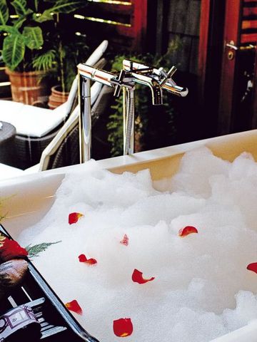 Badezimmer mit gefüllter Badewanne und Rosenblättern