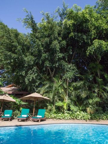 Pool mit grünen Liegestühlen und üppiger Vegetation im Hintergrund