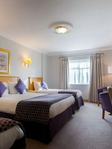 Helles Hotelzimmer mit zwei Doppelbetten und eleganter Einrichtung