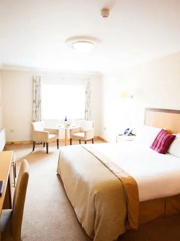 Großes Hotelzimmer mit gemütlichem Doppelbett und Sitzecke