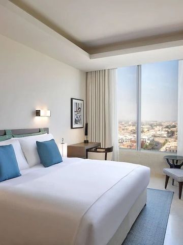 Helles Hotelzimmer mit großem Fenster und Stadtblick.