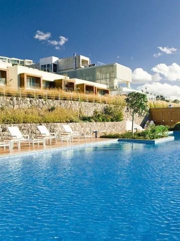 Modernes Hotelgebäude am Hang mit großem Außenpool und Liegestühlen.