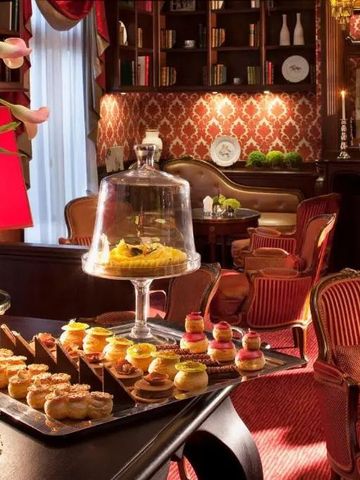 Gemütliche Lounge mit rotem Dekor und Gebäckpräsentation im Hotel Auberge du Jeu de Paume