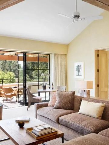 Helles Wohnzimmer einer luxuriösen Suite mit Balkon und Ausblick auf grüne Landschaft.