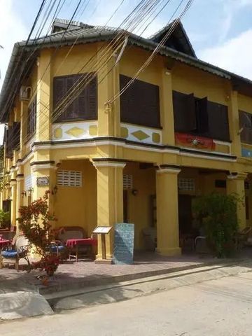 Historische gelbe Hotelfassade mit Balkonen und Palmen