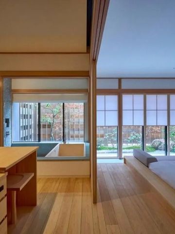 Modern eingerichtetes, lichtdurchflutetes Hotelzimmer mit Ausblick auf einen Privatgarten.