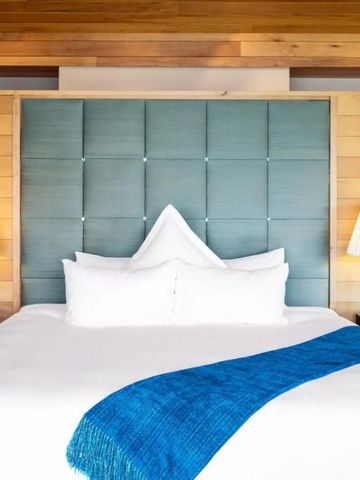 Großes Bett in stilvoller Suite mit Holzwänden und modernem Design