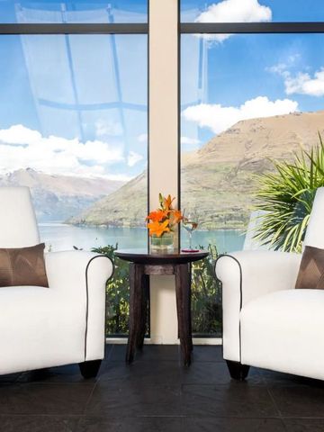 Gemütliche Sessel vor Panoramafenster mit Blick auf Berglandschaft