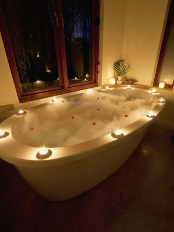 Stimmungsvolle Badewanne mit Kerzen und Schaum in einem luxuriösen Hotelbad
