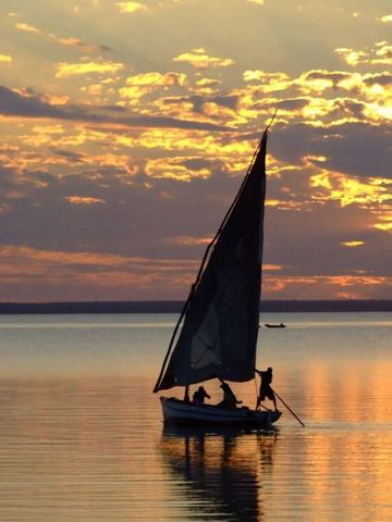 Segelboot auf ruhigem Wasser während eines spektakulären Sonnenuntergangs