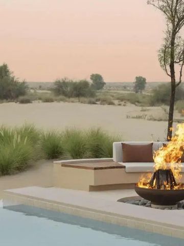 Außenbereich mit Feuerstelle, Pool und Wüstenlandschaft im Hintergrund im Hotel Bab Al Shams