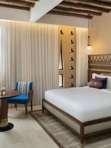 Modernes Hotelzimmer mit großen Fenstern, Doppelbett und eleganten Designakzenten.