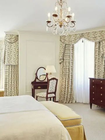 Geräumiges Schlafzimmer mit eleganten Stoffvorhängen und Kronleuchter.