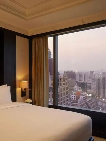 Gemütliche Hotelsuite mit Panoramablick über die Stadt bei Sonnenuntergang.