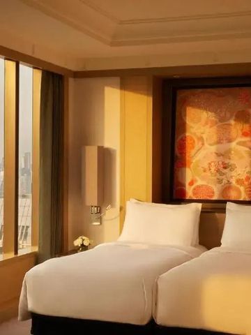 Zweibettzimmer mit großem Fenster und Stadtansicht im Hintergrund.