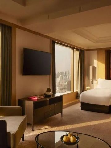 Großzügige Suite mit Sitzbereich und Blick auf die Skyline.