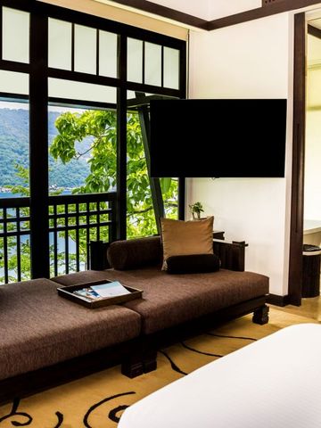 Luxuriöse Suite mit Blick auf tropische Landschaft von großen Fenstern