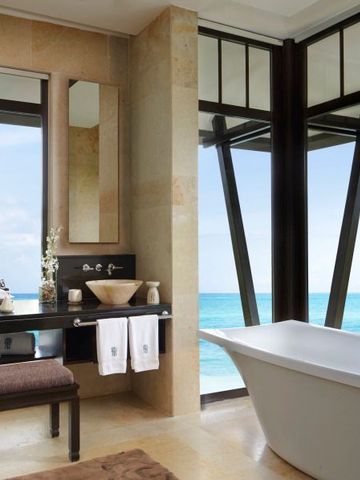 Badezimmer mit freistehender Badewanne und Meerblick durch große Fenster