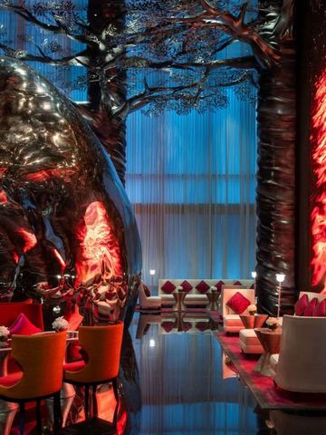 Luxuriöse Hotellounge mit roten und goldenen Akzenten sowie skulpturalen Kunstwerken