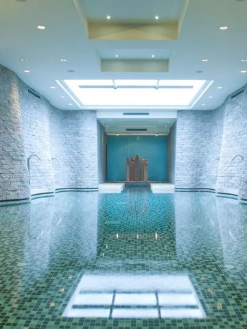 Großer Innenpool mit Steinwänden und hellem Oberlicht