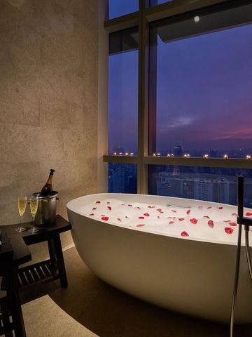 Luxuriöse Badewanne mit Rosenblättern und Stadtblick