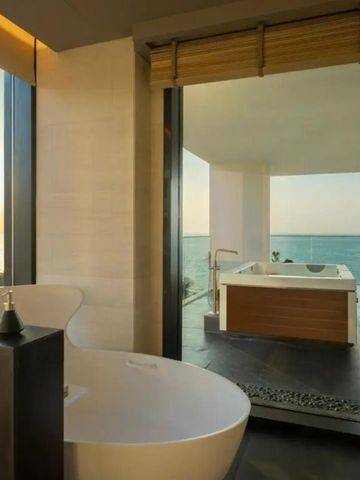 Luxusbad mit freistehender Badewanne und Blick auf Sonnenuntergang über dem Meer