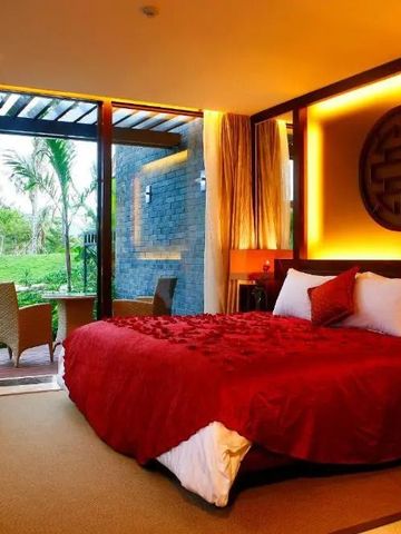 Geräumiges Zimmer mit roter Bettdecke und Blick auf den Garten im Banyan Tree Sanya