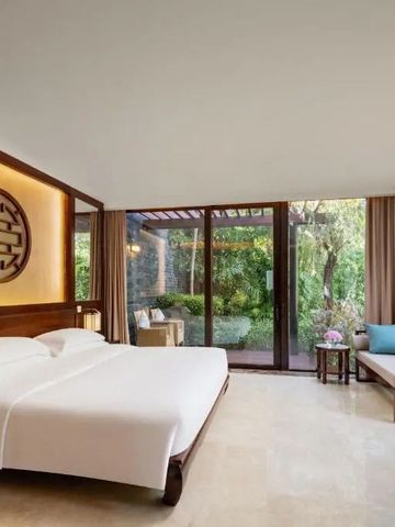 Modernes Zimmer mit großem Fenster und Blick auf tropischen Garten im Banyan Tree Sanya