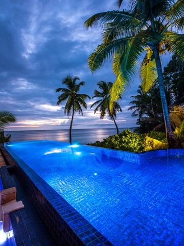 Infinity Pool im Banyan Tree Sanya Resort bei Sonnenuntergang mit Palmen und Meerblick.