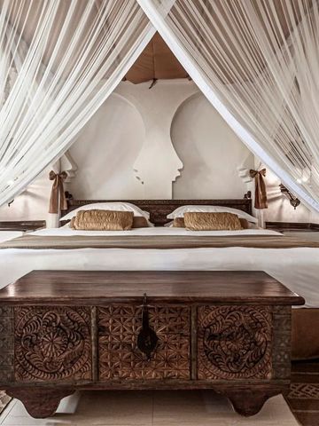 Luxuriöses Schlafzimmer mit Baldachinbett und edlem Holzmöbel.