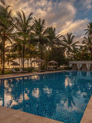 Swimmingpool umgeben von Palmen bei Sonnenuntergang