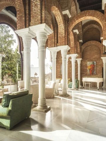 Elegante weiße Marmorsäulen und große Bogenfenster in einer sonnigen Lounge.