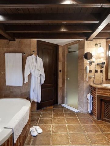 Luxuriöses Badezimmer mit freistehender Badewanne und rustikaler Decke