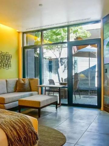 Heller Wohnbereich mit Sofa und Zugang zur Terrasse im Hotelzimmer