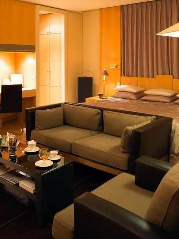 Elegantes Hotelzimmer mit Doppelbett und Sitzbereich in warmen Holztönen