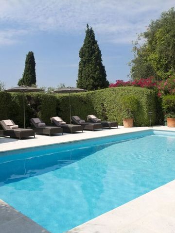 Außenpool mit Liegen umgeben von gepflegten Hecken und Bäumen