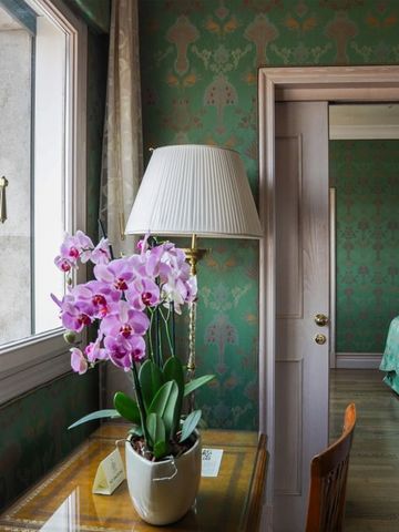 Elegantes Zimmer mit floraler Tapete und Orchideen auf einem Tisch